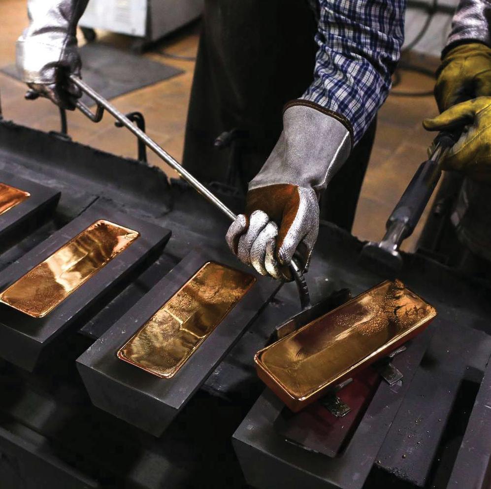 Worker handling unrefined dor&eacute; bars in casting molds