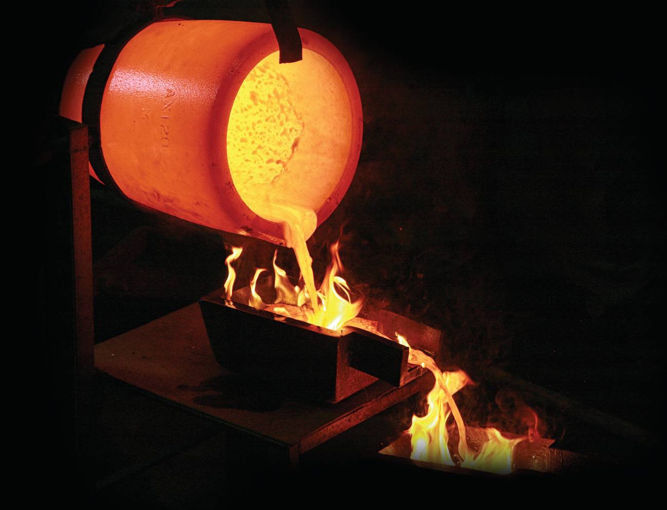 A crucible pouring molten gold into a mold