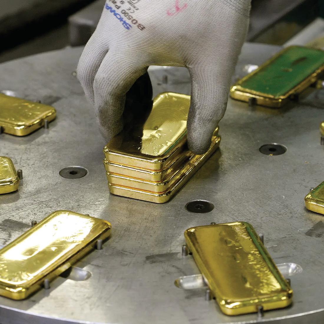 Gloved hands stacking finished gold bars